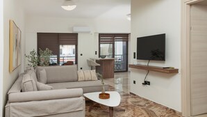 En moderne stue med sofa, sofabord, fjernsyn og en balkon.