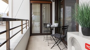En balkon med et bord, stole, en potteplante og en ventilator.