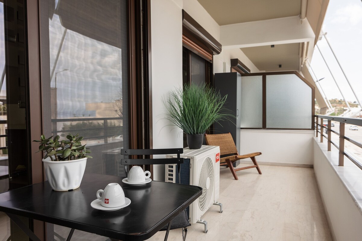Ein Balkon mit Tisch, zwei weißen Tassen, einem Blumentopf und einem Stuhl.