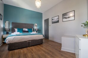 Ein Schlafzimmer mit Bett, Nachttischen, Schreibtisch und einer Tür.