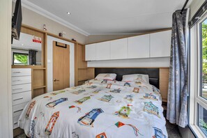 A bedroom with a bed, a wardrobe, a mirror, and a window with curtains.