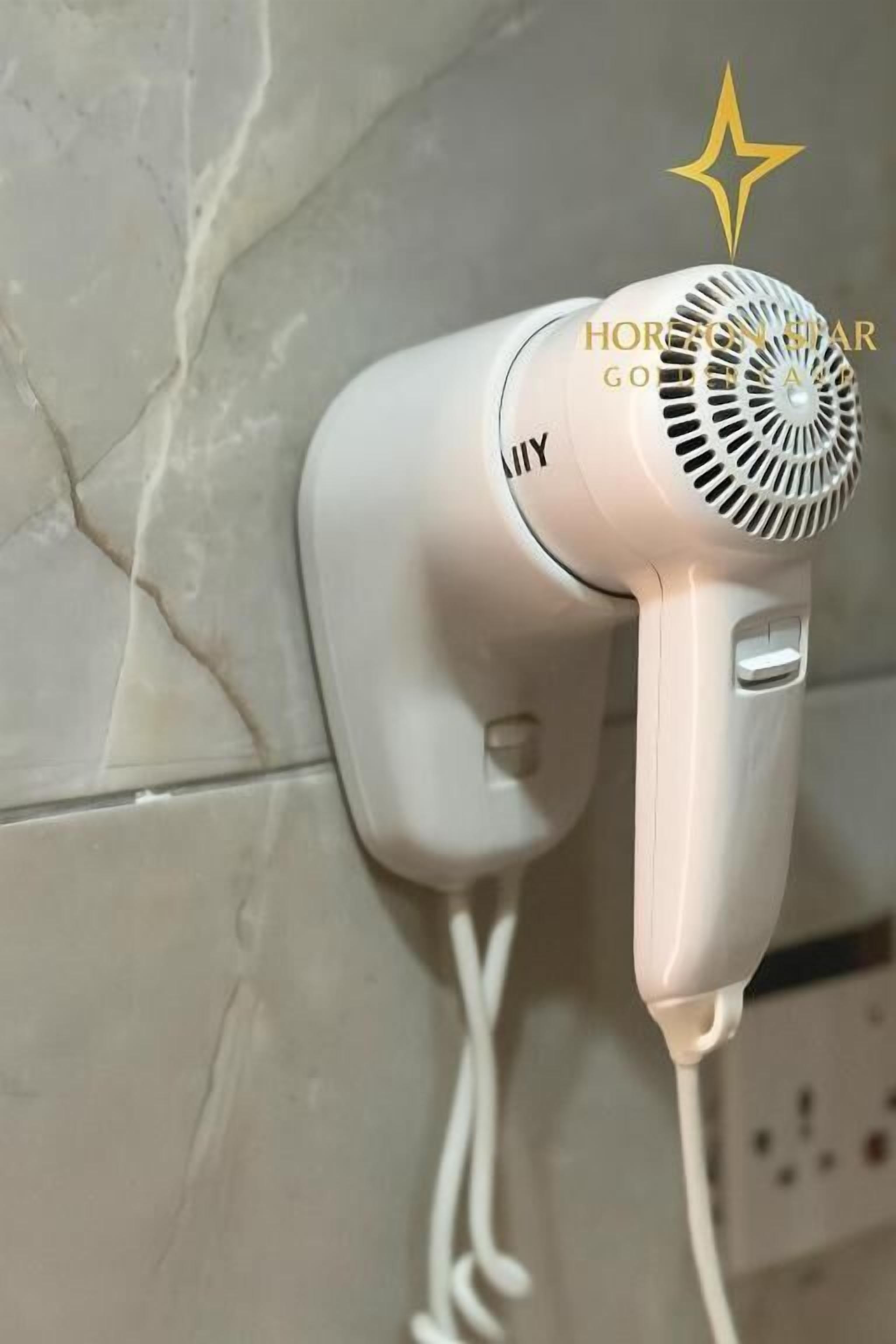 A hair dryer mounted on a wall with a visible power cord.