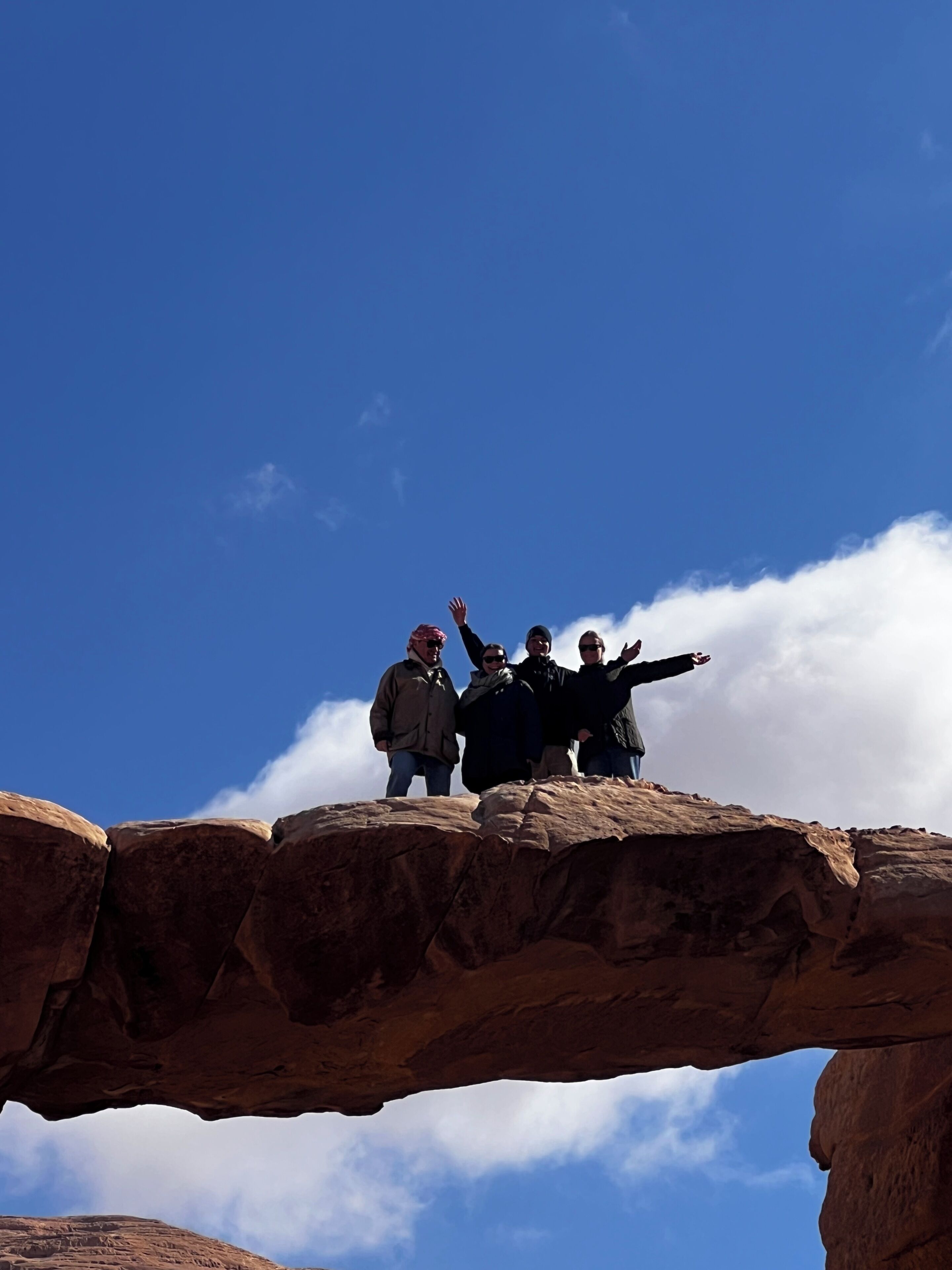 A group of people standing on a rock formation with a clear blue sky in the background.