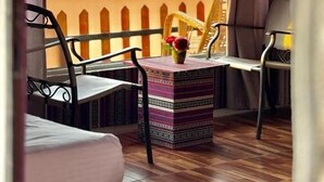 A room with a large window, a small table with a vase, two chairs, and a bed. - Horizon Star Golden Camp (Wadi Rum)