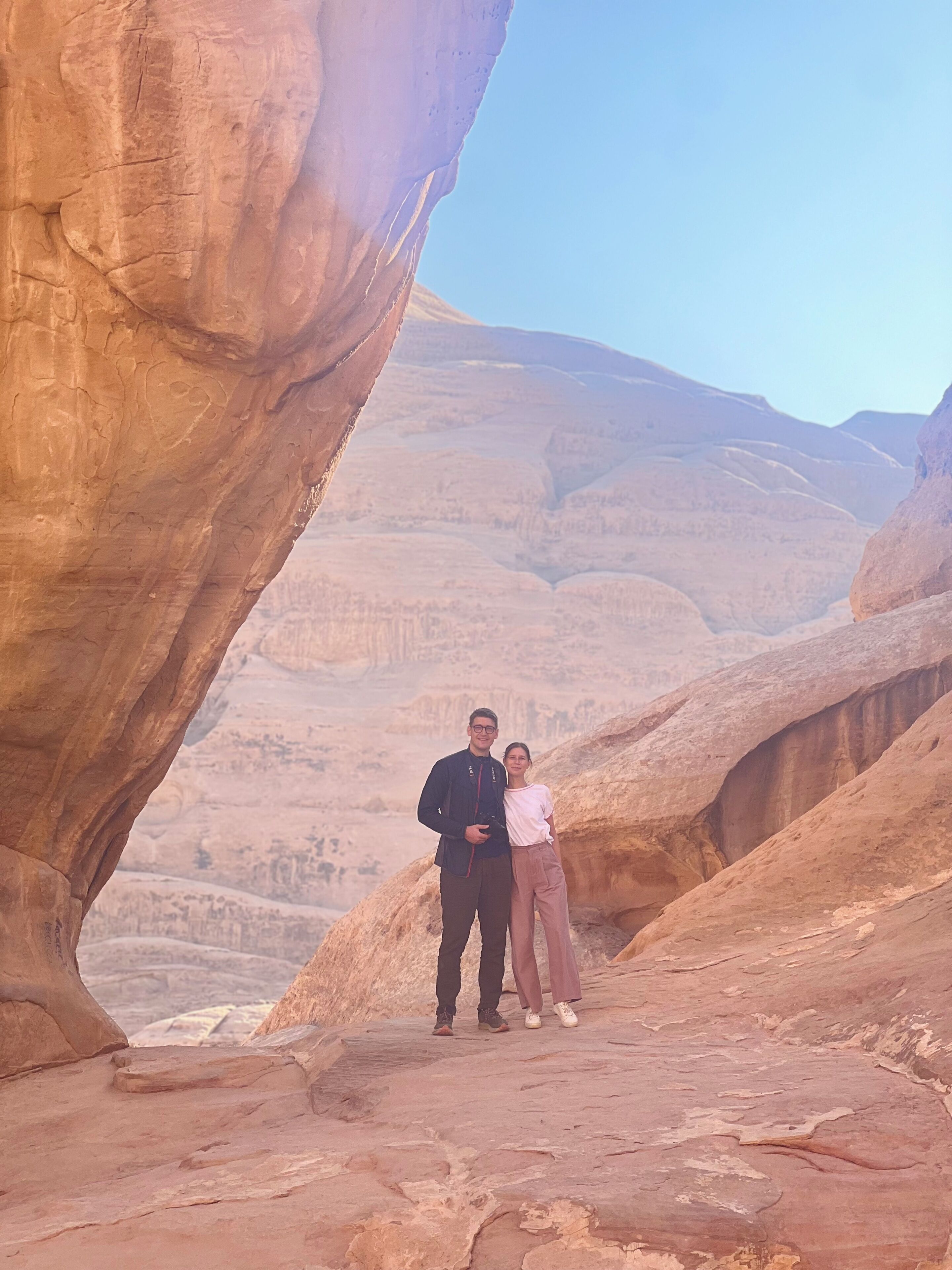 A couple standing on a rocky outcrop with a vast canyon in the background.