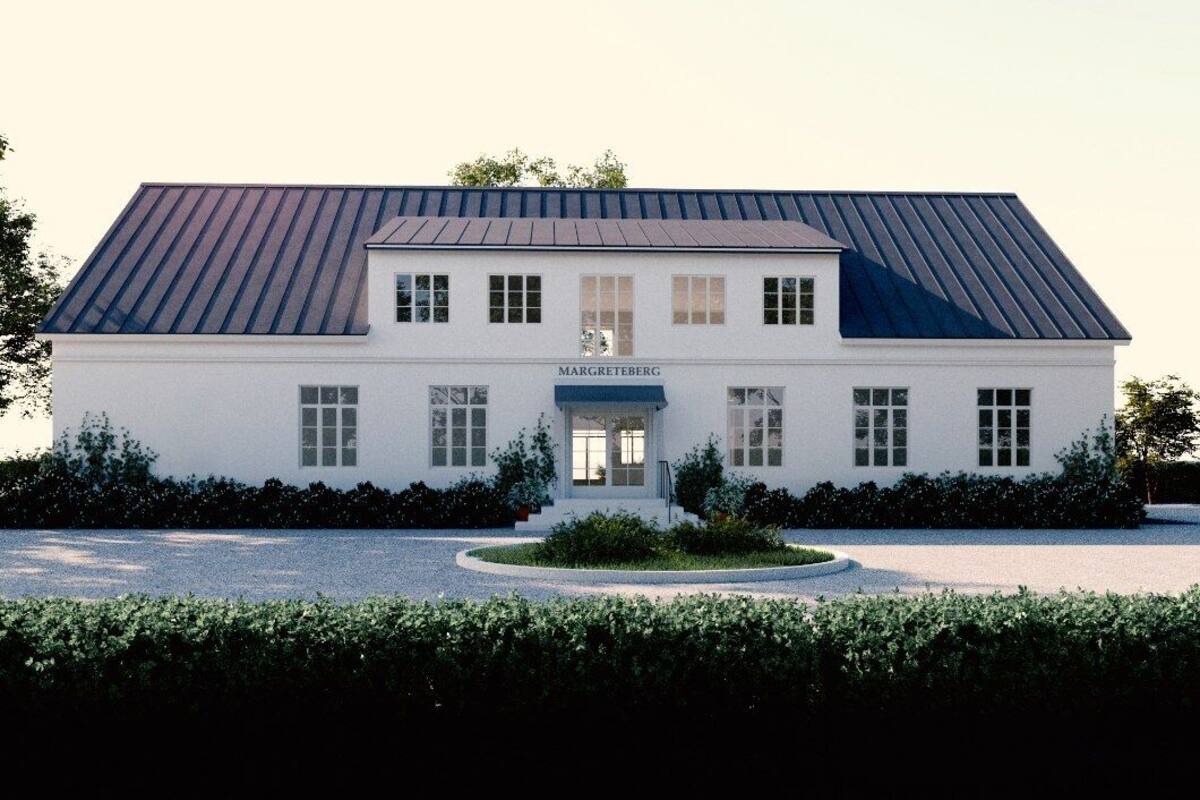 A two-story building with a flat roof, a central entrance, and a nameplate.