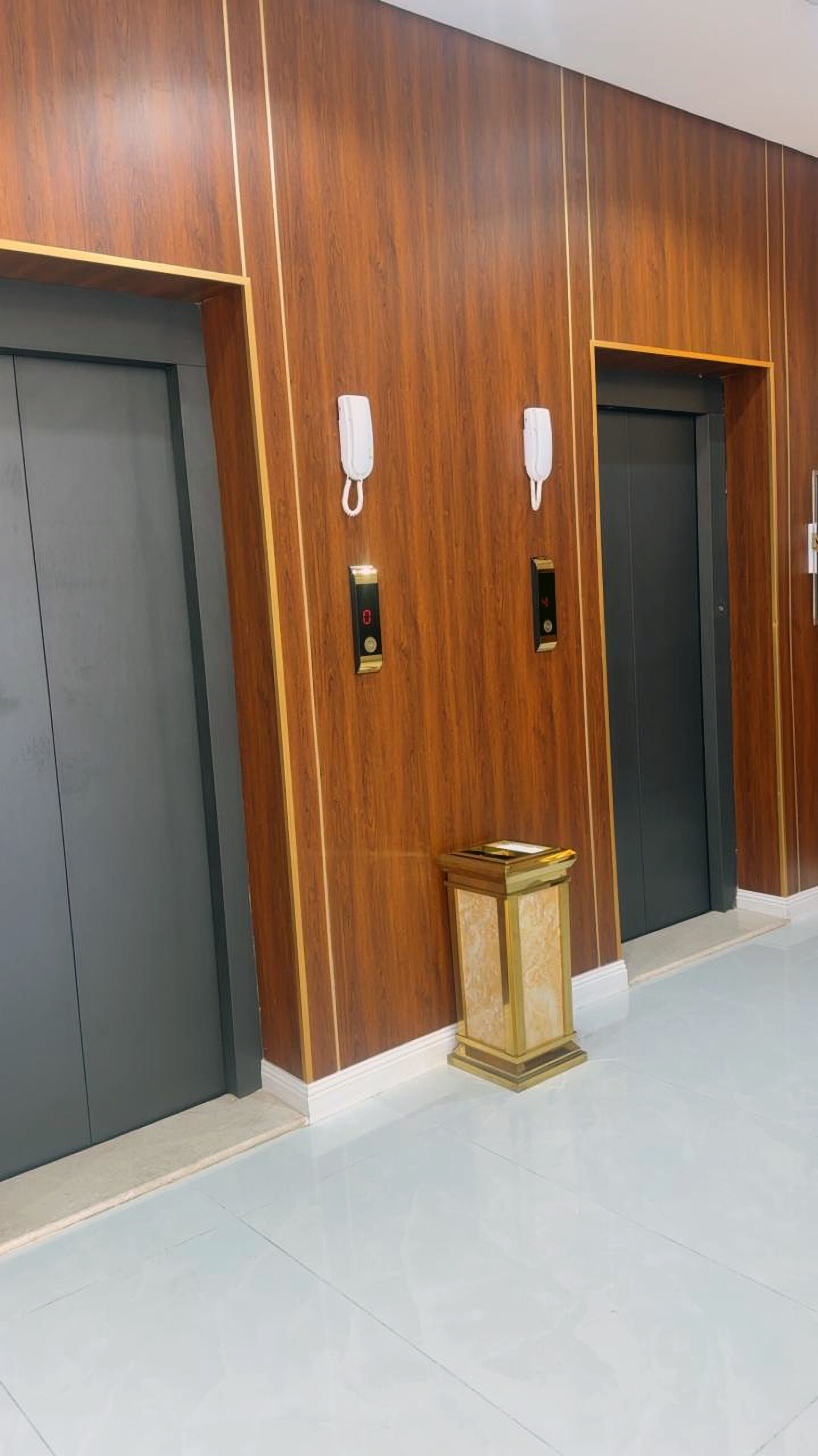 A hallway with two elevators, each with a phone and a control panel.
