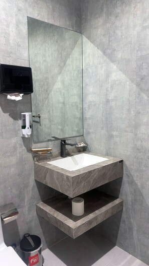 Un bagno moderno con uno specchio grande, un lavabo incassato e un portasciotto.