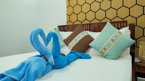 Un lit avec un doudou bleu, des oreillers à motifs géométriques et une tête de lit en bois ornée d’un motif en forme de nid d’abeilles.