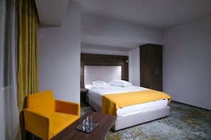 Une chambre d’hôtel avec un lit, une chaise, une table et une table de chevet.