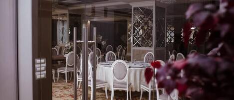 Un comedor con mesas redondas, sillas blancas y una alfombra estampada.