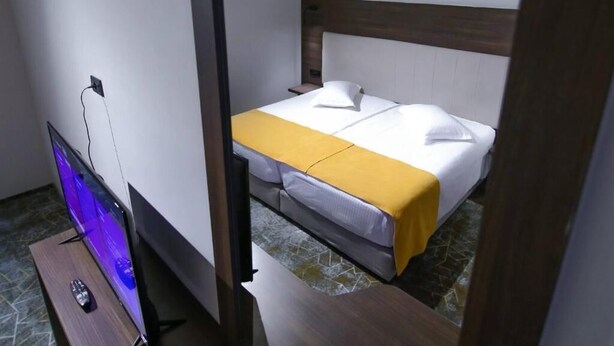 A hotel room with a bed, a TV, and a remote control.