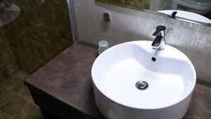 A bathroom with a white sink, a mirror, and a brown countertop.