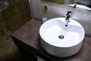 A bathroom with a white sink, a mirror, and a brown countertop.