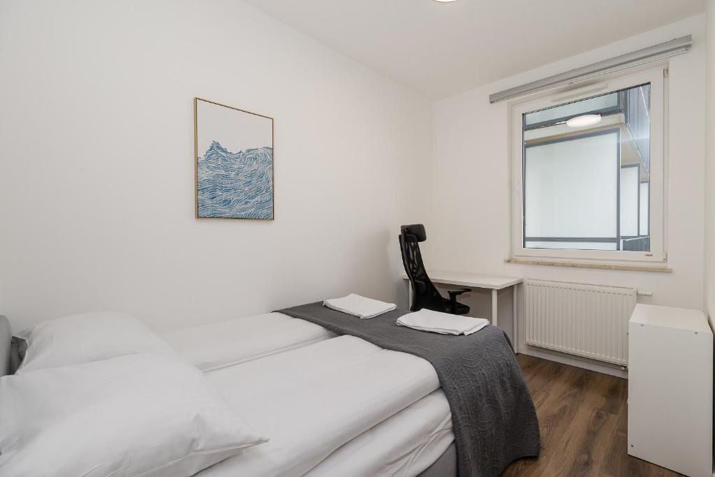 Hotelkamer met een bed, een bureau, een stoel, een radiator en een raam.