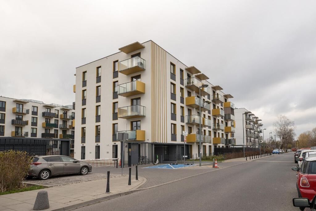 Um edifício residencial com vários andares, varandas, área de estacionamento e céu limpo.