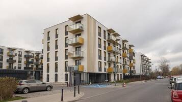 Um edifício residencial com vários andares, varandas, área de estacionamento e céu limpo.