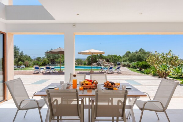 A dining area with a table set for breakfast, overlooking a pool and garden. - SON JERONIO (Muro)