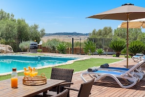 A poolside area with a table, chairs, and lounge chairs. - SON JERONIO (Muro)