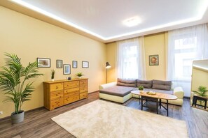 Ein Wohnzimmer mit einer Couch, einem Couchtisch, einem Holzschrank und einer großen Kübelpflanze.