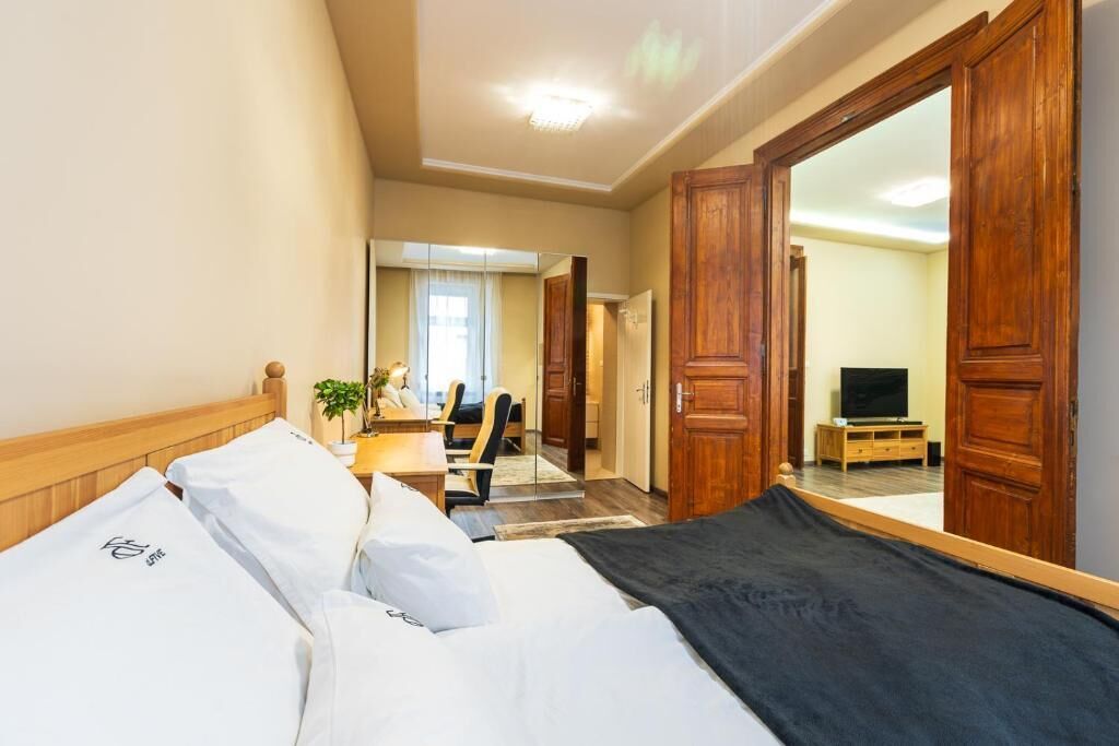 Ein Hotelzimmer mit einem Bett, einem Schreibtisch, einem Sessel, einem Fernseher und einem Spiegel.