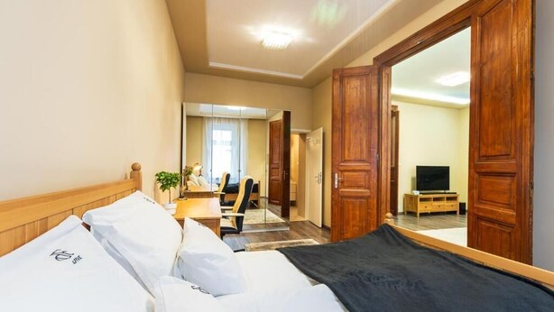 Ett hotellrum med en säng, ett skrivbord, en stol, en tv och en spegel.