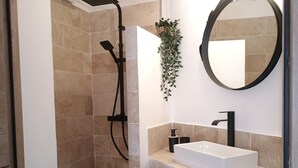 Ein Badezimmer mit Dusche, Waschbecken, Spiegel und einer Pflanze.