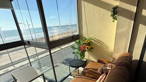 Ein Balkon mit Glastür, einer Couch, einem kleinen Tisch und einem Blumentopf.