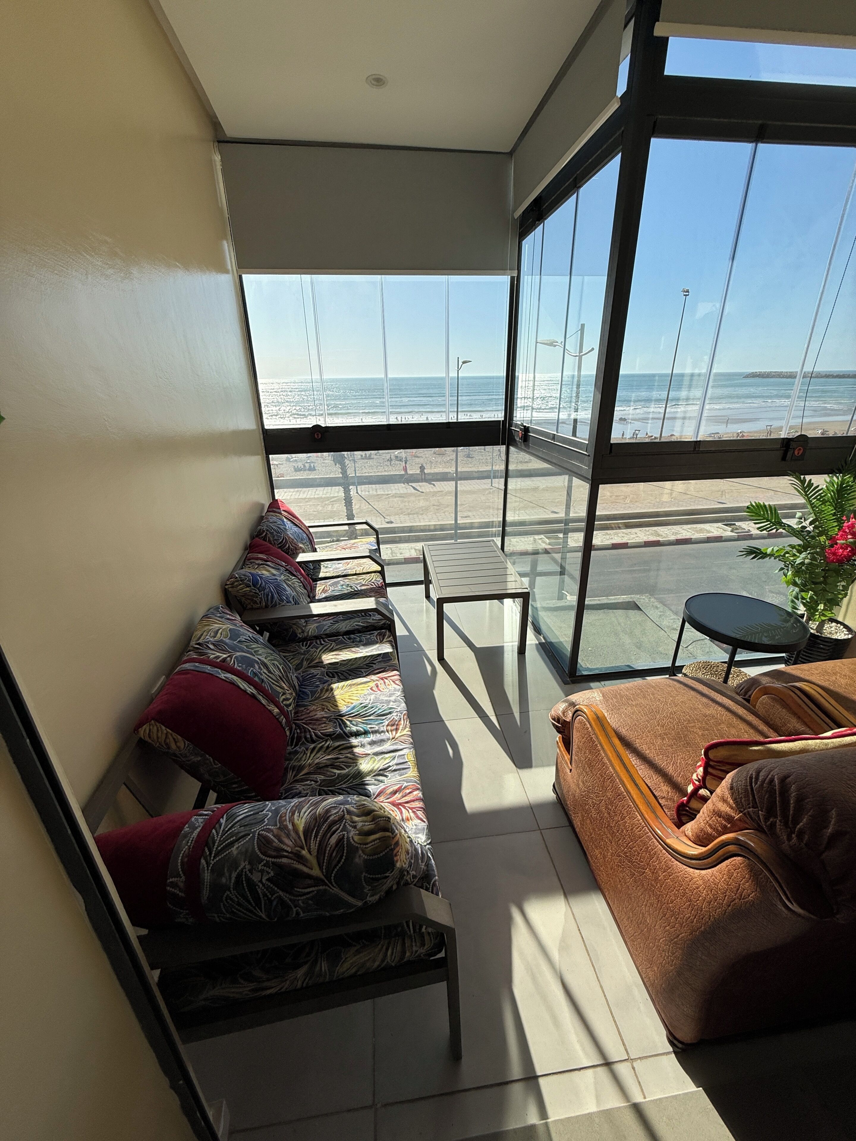 A balcony with a sofa and a table, overlooking a beach.
