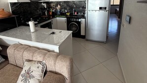 Eine moderne Küche mit weißen Schränken, einer schwarzen Arbeitsplatte, einem Edelstahlkühlschrank und einer Waschmaschine.
