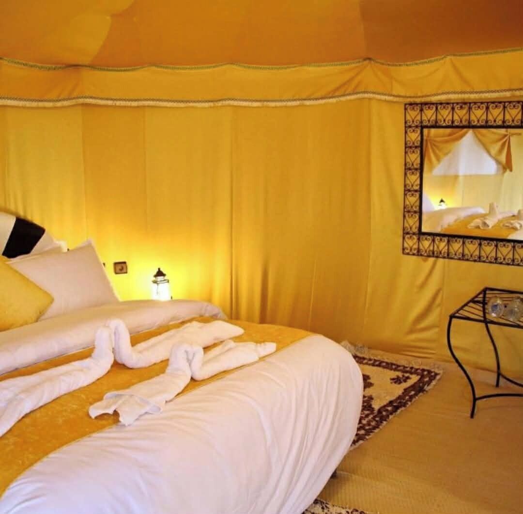 A room with a bed, a nightstand, a mirror, and a lamp.