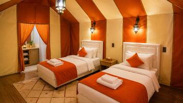 A bedroom with two beds, a nightstand, a lamp, and a window with curtains.