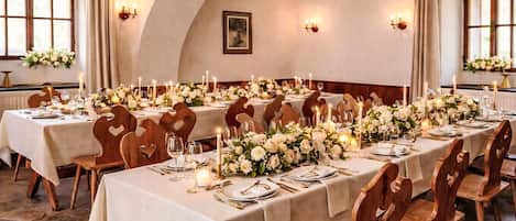 A banquet hall with long tables, wooden chairs, and floral centerpieces.