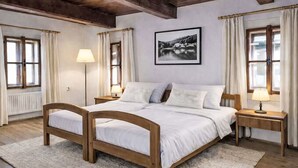 Een slaapkamer met een houten bed, twee nachtkastjes, een vloerlamp en een lijst met een afbeelding aan de muur.