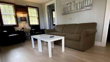 A living room with a white coffee table, a brown sofa, and a painting on the wall.