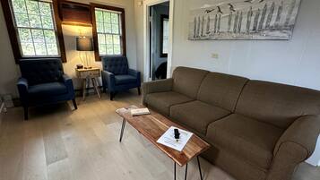 A living room with a brown sofa, two blue armchairs, a wooden coffee table, and a lamp.