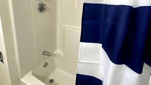 Une douche avec un rideau de douche rayé de blanc et de bleu, une pomme de douche en chrome et un pommeau de douche amovible.
