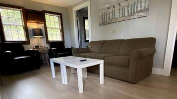 Un salon avec une table basse blanche, un canapé marron et un tableau accroché au mur.