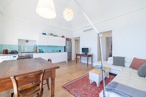 Eine moderne Küche mit weißen Schränken, einem Holztisch und einem roten Teppich.