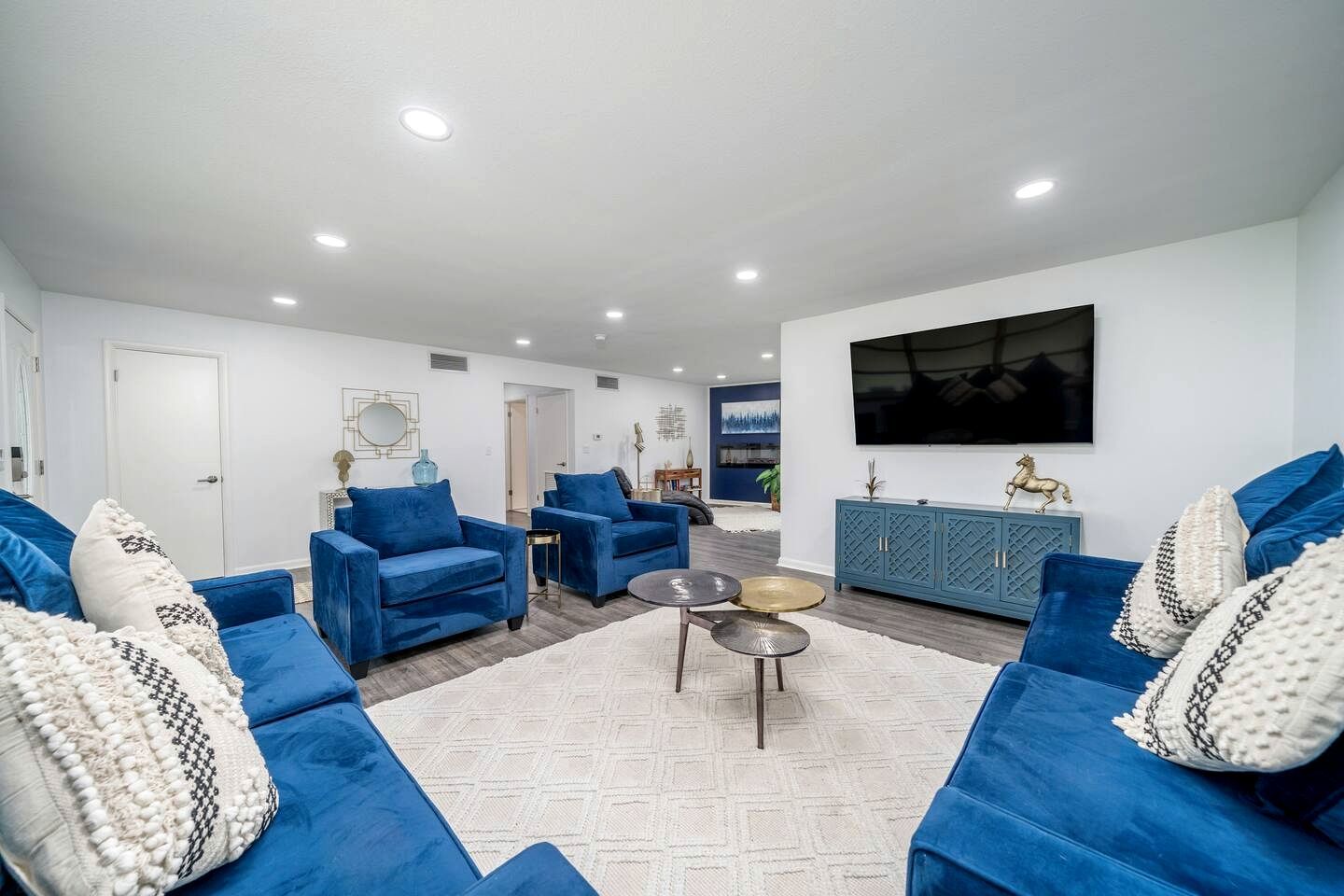 Un salon moderne avec des canapés bleus, une table basse et un téléviseur fixé au mur.
