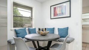 Un coin repas avec une table ronde, quatre chaises, un bol décoratif et un tableau abstrait encadré accroché au mur.