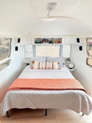 Un interior acogedor con una cama, una mesita de noche y un ventanal.