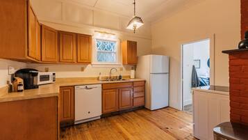 Una cocina con armarios de madera, microondas, lavavajillas, refrigerador y ventana con vistas.