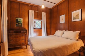 A wooden-paneled room with a bed, a dresser, a window with curtains, and framed pictures on the walls. - Spacious Waterfront Cabin with Private Dock Near Lake George & Saratoga Springs, Corinth, NY (Corinto)