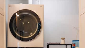 A laundry room with stacked towels on a shelf and a washing machine.