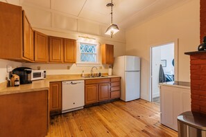Una cocina con armarios de madera, microondas, lavavajillas, refrigerador y ventana con vistas.