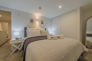 Ein Schlafzimmer mit Bett, Nachttischen, einer Wandlampe und einem Spiegel.