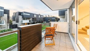Ein Balkon mit Blick auf angrenzende Häuser, einen Holzzaun und zwei Holzstühle.