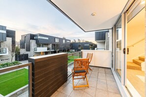 A balcony with a view of neighboring houses, a wooden fence, and a pair of wooden chairs. - Serene CBD Stay | 2BR | Balcony + Laundry (Christchurch)