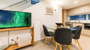 Eine moderne Küche mit Essbereich, einem Flachbildfernseher und einem Fenster mit Jalousien.